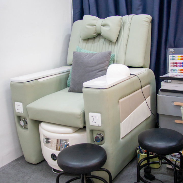 A comfortable sage green chair in the Reve nail lounge