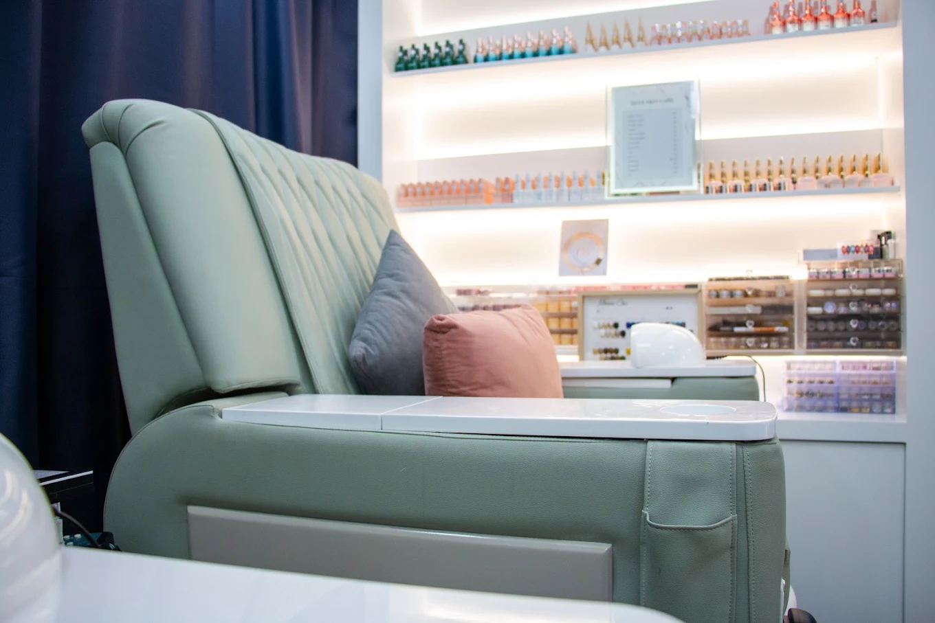 Sage green manicure seating with a display of nail colours